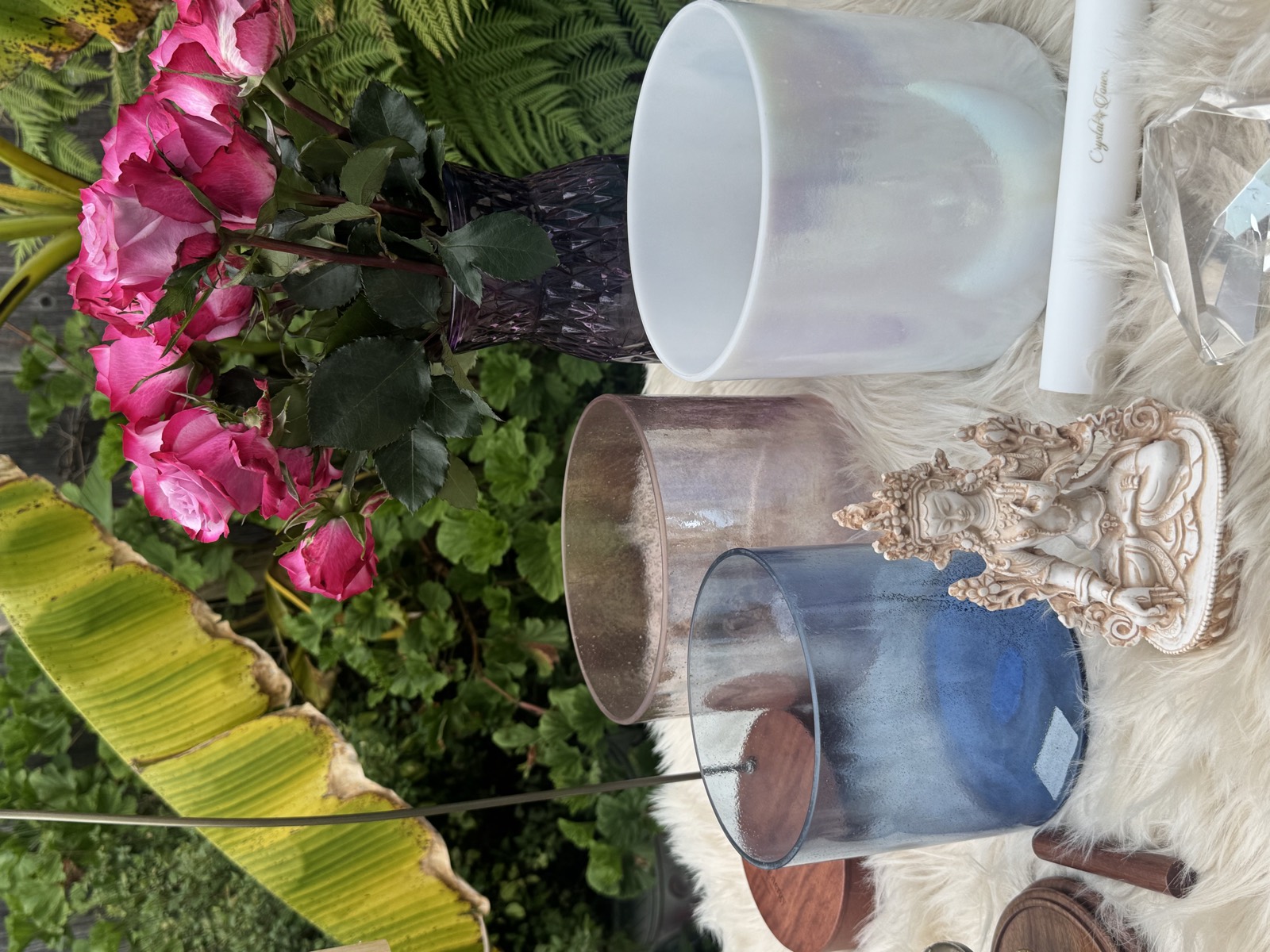 Quartz crystal singing bowls with White Tara statue and roses